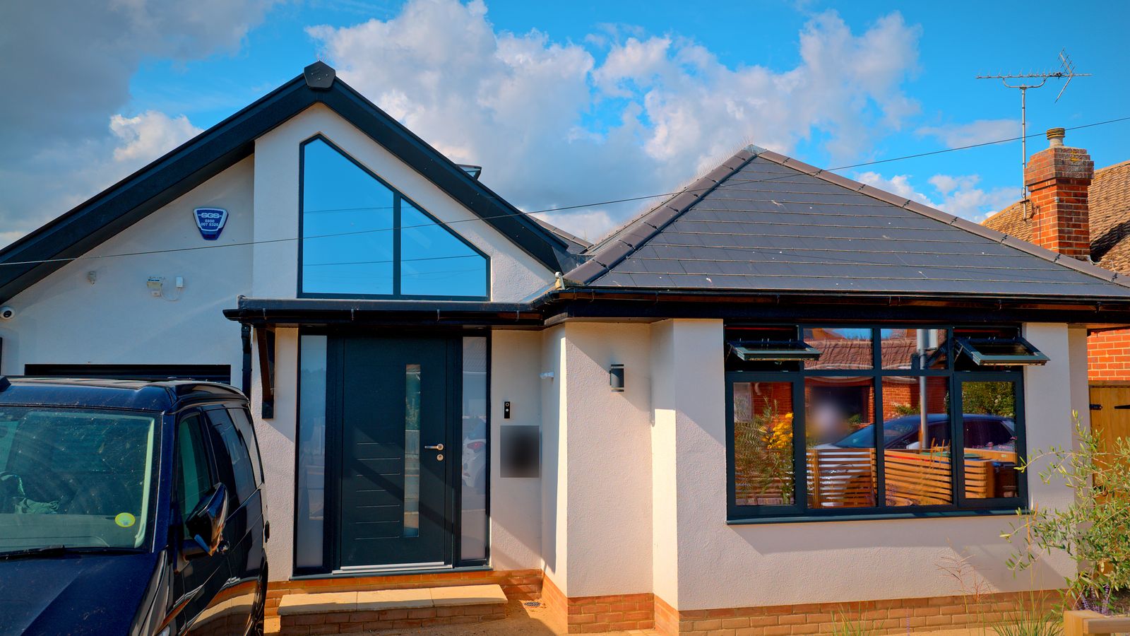 Front elevation with white render, a glazed gable and an anthracite front door