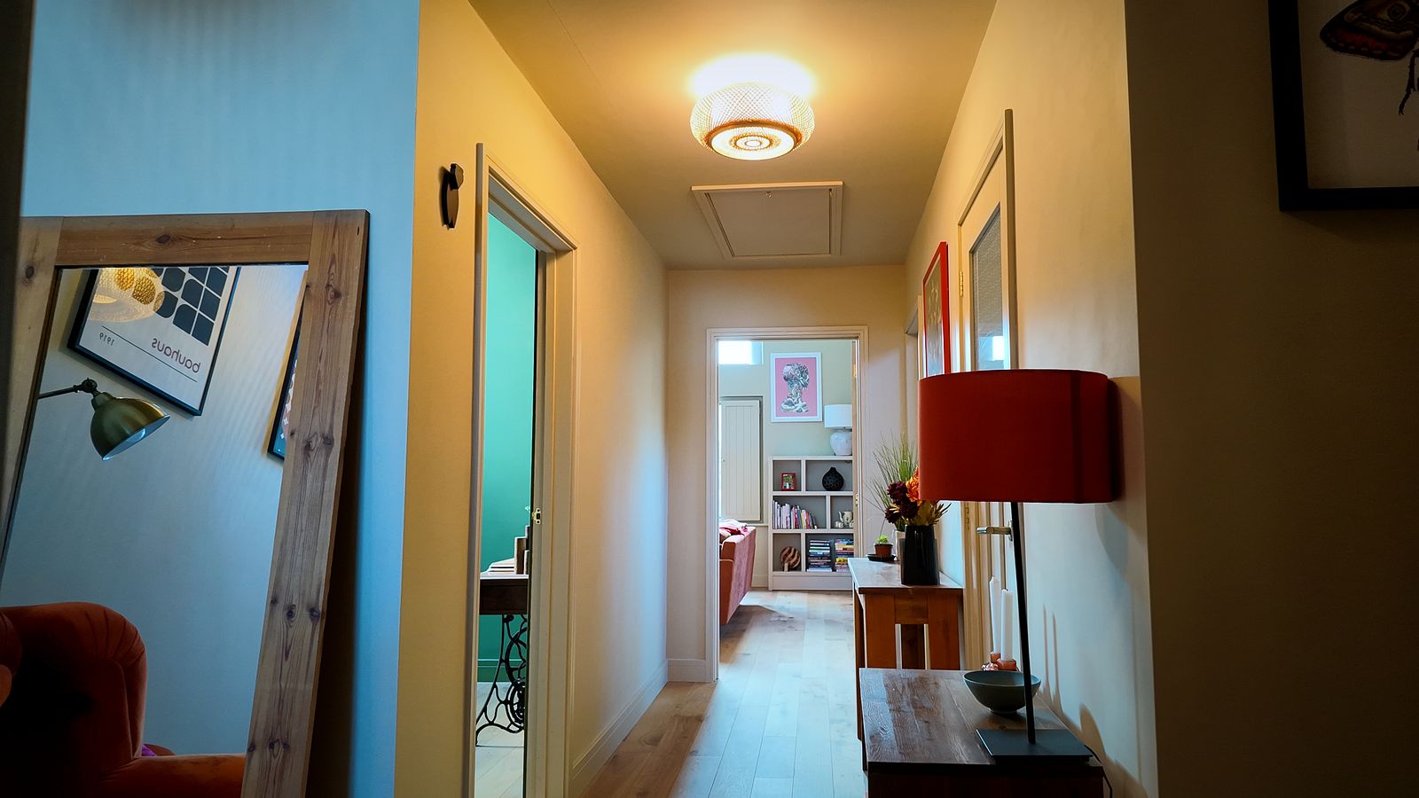 Hallway with a mirror, table lamp and wood flooring