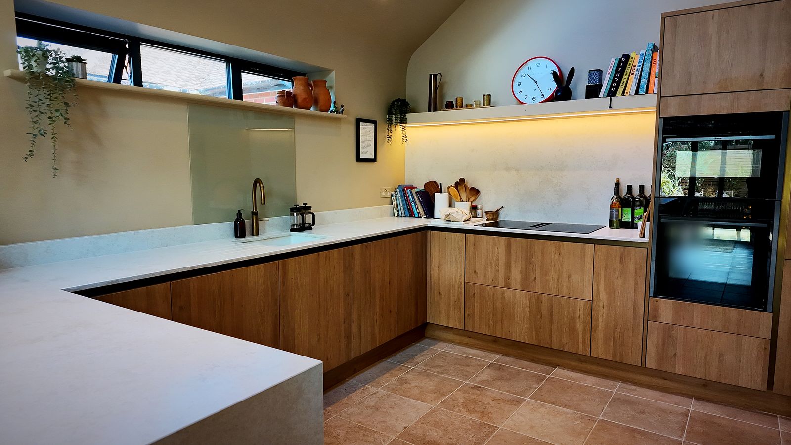 Kitchen with wood-effect units, white worktops and built-in ovens